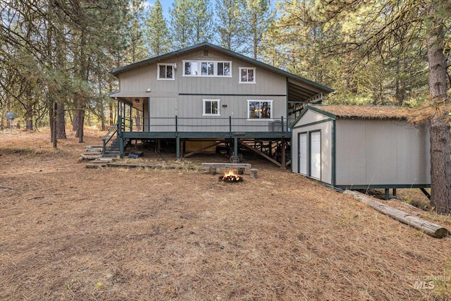 rear view of property with a deck, an outbuilding, stairway, a shed, and an outdoor fire pit