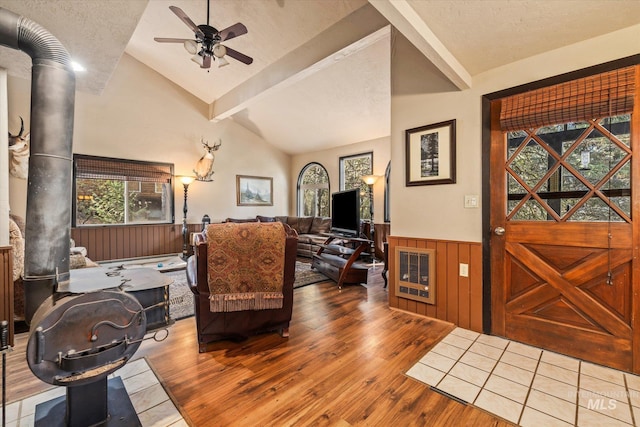 foyer entrance featuring ceiling fan, wood walls, wood finished floors, a wainscoted wall, and lofted ceiling with beams