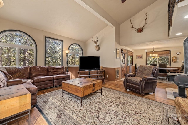 living area with a wainscoted wall, wood finished floors, and lofted ceiling