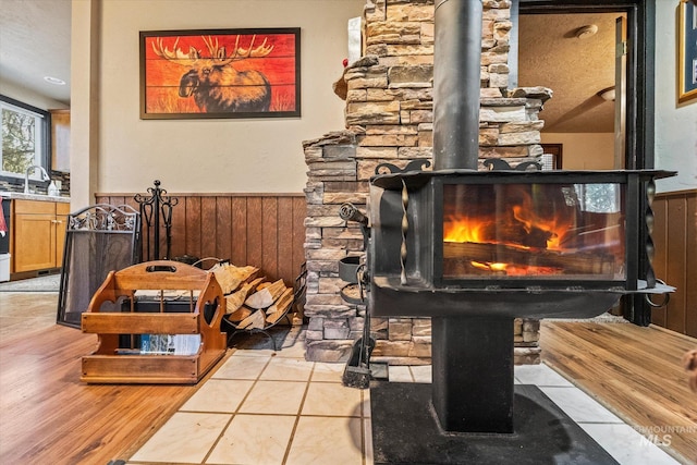 room details featuring a sink, a wood stove, wainscoting, and wood walls