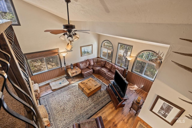 living room featuring a textured ceiling, hardwood / wood-style flooring, ceiling fan, and lofted ceiling