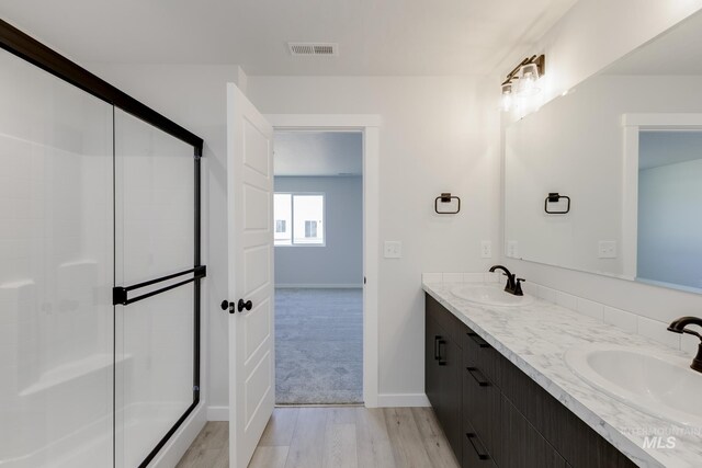 5303 E Grizzly St, Nampa, ID 83687 - bathroom featuring a stall shower, double vanity, wood finished floors, and baseboards