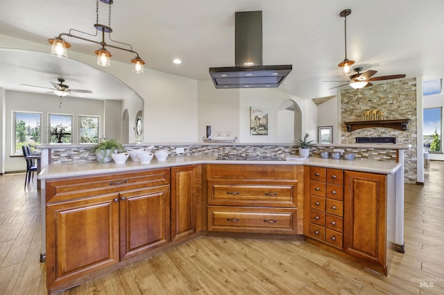 kitchen with decorative light fixtures, backsplash, exhaust hood, ceiling fan, and light hardwood / wood-style floors