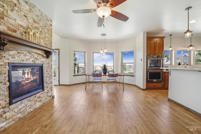 dining area with sink, light hardwood / wood-style flooring, a large fireplace, and ceiling fan