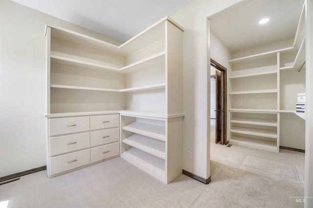 walk in closet featuring light colored carpet