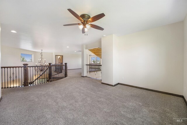 spare room featuring ceiling fan with notable chandelier and carpet floors