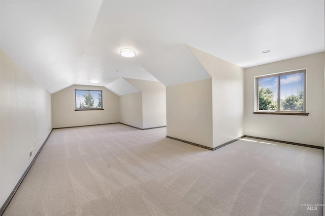 bonus room with light carpet and vaulted ceiling