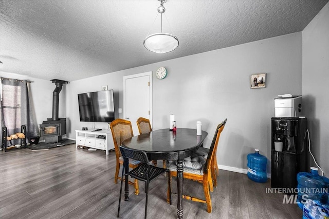 dining space featuring a wood stove, dark wood-style floors, baseboards, and a textured ceiling