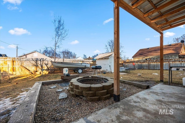 view of patio with a shed, an outdoor fire pit, an outdoor structure, and a fenced backyard