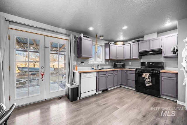 kitchen featuring black appliances, under cabinet range hood, french doors, and gray cabinetry