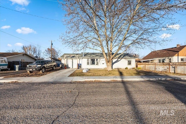 single story home featuring a garage, a residential view, concrete driveway, and fence