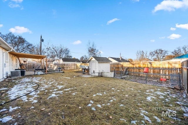 snowy yard featuring cooling unit, a fenced backyard, an outdoor structure, and a storage shed