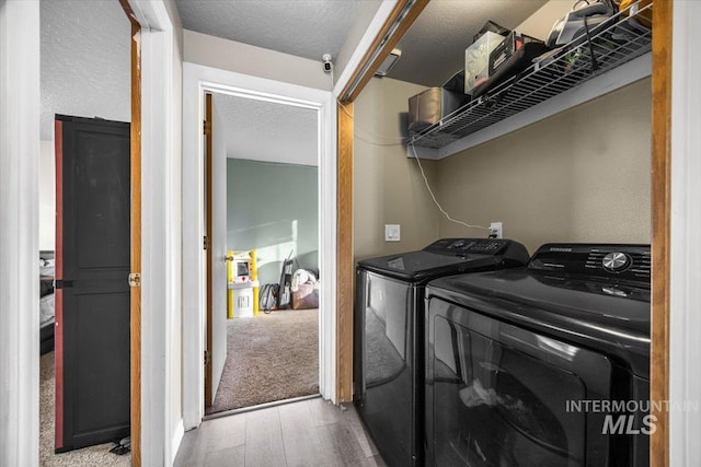 washroom featuring a textured ceiling, laundry area, light wood-style floors, and washer and dryer