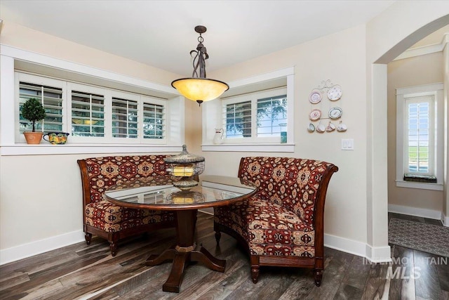 sitting room featuring arched walkways, baseboards, and wood finished floors