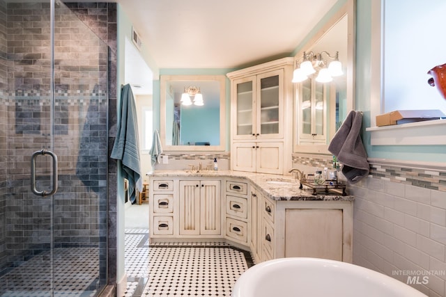 bathroom with a sink, a shower stall, double vanity, and visible vents