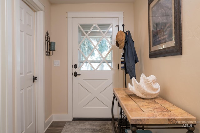 doorway to outside featuring baseboards and dark wood-style flooring