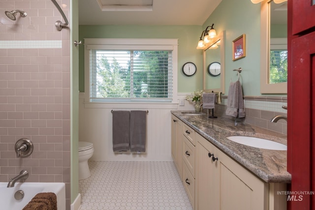bathroom featuring double vanity, a sink, a wainscoted wall, and toilet