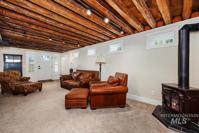 living room featuring a wood stove, rail lighting, carpet, baseboards, and wood ceiling