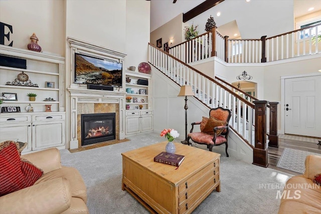 living area featuring a tiled fireplace, stairs, a high ceiling, carpet, and recessed lighting