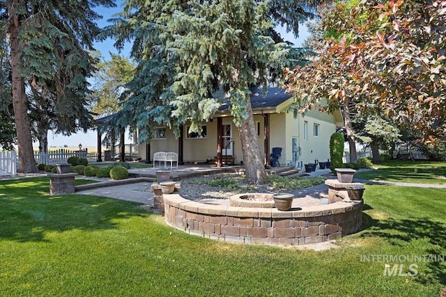 view of front of home featuring stucco siding, fence, a front yard, and a patio