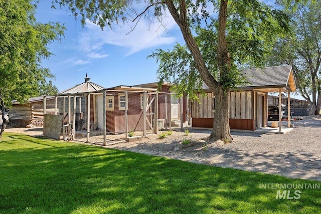 back of property featuring exterior structure, an outbuilding, and a yard