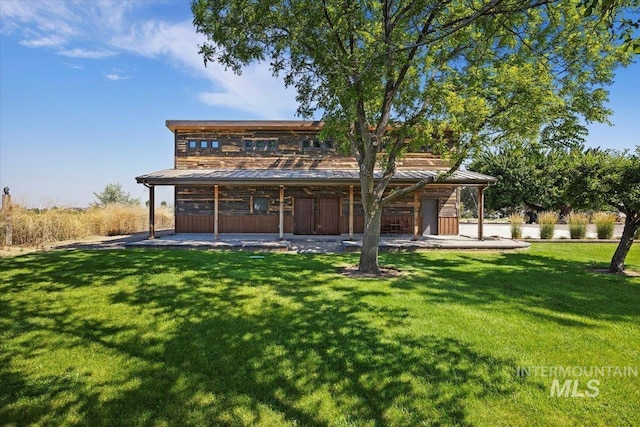 rear view of property with a lawn, a standing seam roof, and metal roof