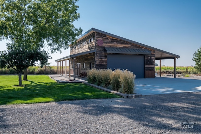 view of property exterior with a lawn, an outbuilding, a standing seam roof, and concrete driveway