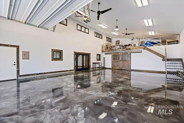 garage featuring baseboards, ceiling fan, and electric panel