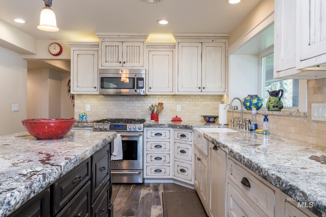 kitchen with a sink, appliances with stainless steel finishes, light stone countertops, and backsplash