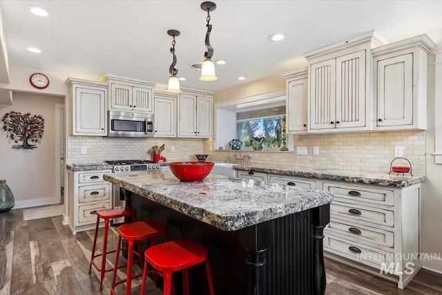 kitchen featuring a kitchen island, decorative light fixtures, tasteful backsplash, stainless steel microwave, and dark wood-type flooring