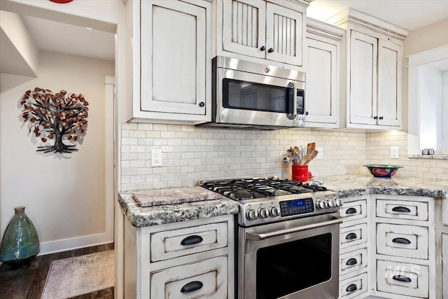 kitchen featuring decorative backsplash, dark wood-style flooring, light stone countertops, baseboards, and stainless steel appliances