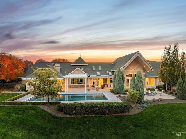 rear view of house featuring a patio, a lawn, and an outdoor pool