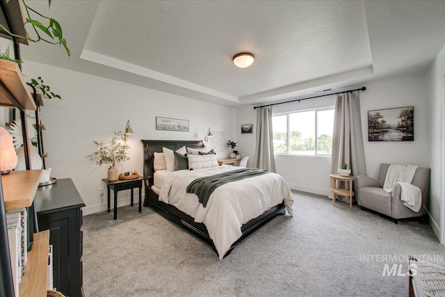 bedroom with a tray ceiling, light colored carpet, and baseboards