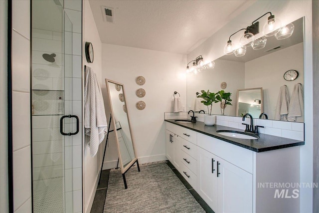 bathroom featuring a shower stall, double vanity, and baseboards