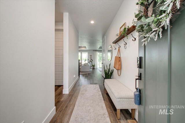 corridor featuring wood finished floors, baseboards, a textured ceiling, and recessed lighting
