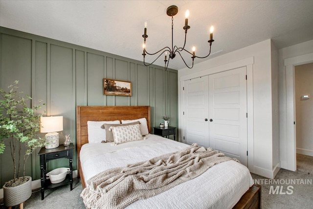 bedroom featuring a decorative wall, a chandelier, light carpet, a closet, and baseboards