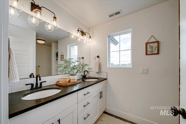 bathroom with baseboards and double vanity