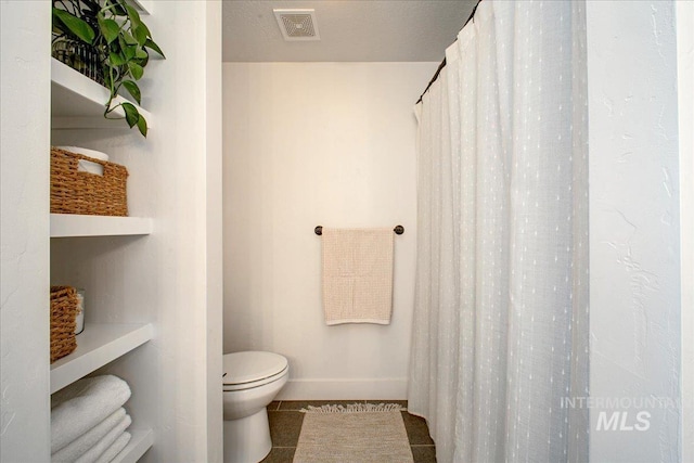 bathroom with toilet, tile patterned floors, and baseboards