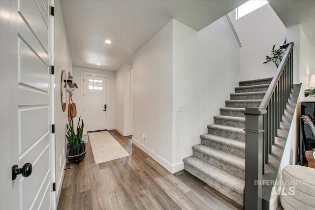 entryway featuring stairway, wood finished floors, baseboards, and recessed lighting