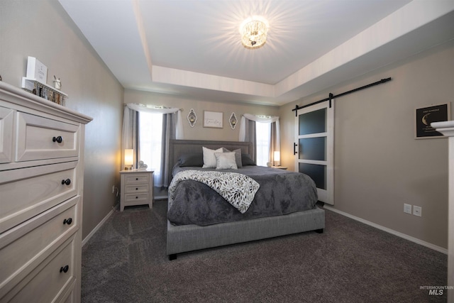 bedroom featuring dark colored carpet, multiple windows, a tray ceiling, and a barn door