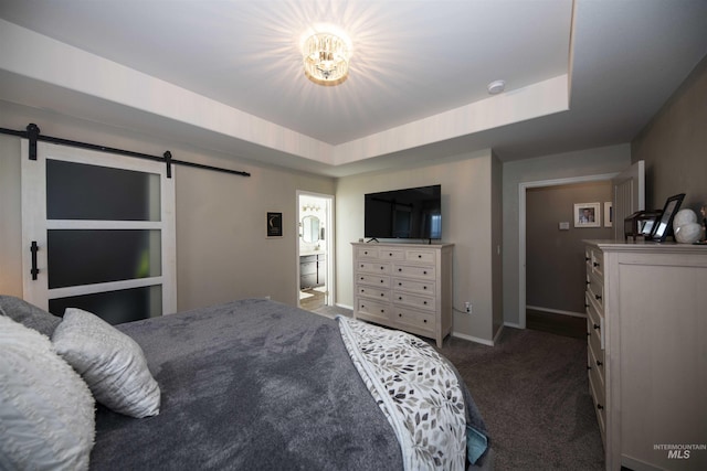 bedroom with a raised ceiling, dark carpet, and a barn door