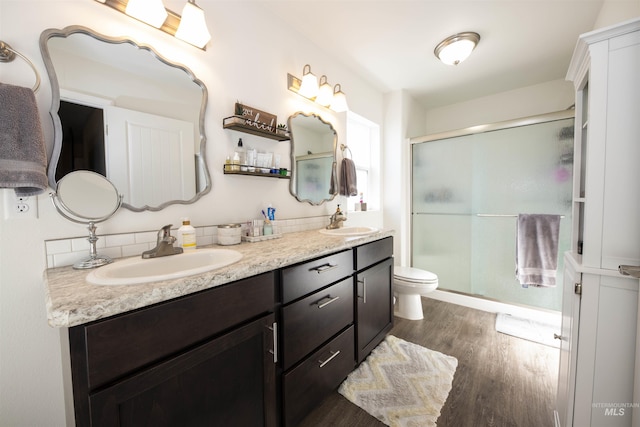 full bath featuring toilet, a stall shower, a sink, and wood finished floors