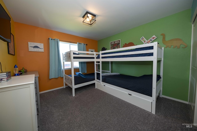 bedroom with dark colored carpet and baseboards