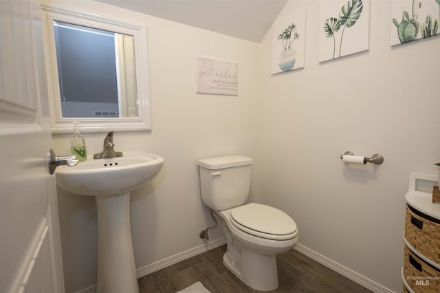 half bathroom featuring toilet, a sink, baseboards, and wood finished floors