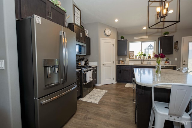 kitchen with appliances with stainless steel finishes, a breakfast bar area, dark wood-type flooring, a center island, and dark brown cabinets