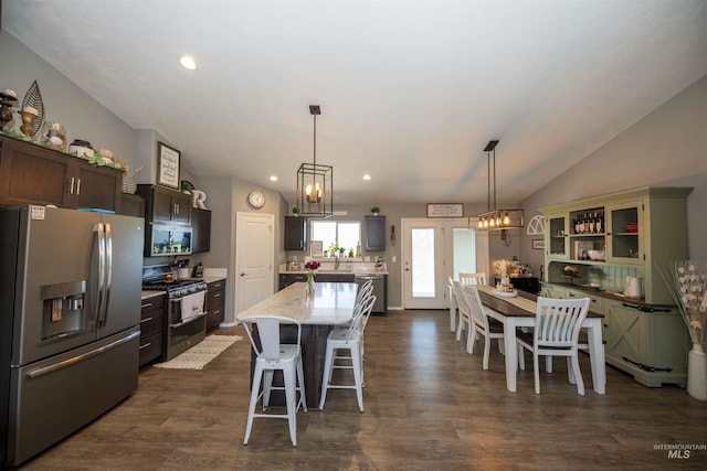 kitchen featuring lofted ceiling, appliances with stainless steel finishes, a kitchen island, dark brown cabinets, and a kitchen bar