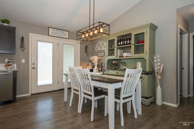 dining room with dark wood-type flooring, vaulted ceiling, and baseboards