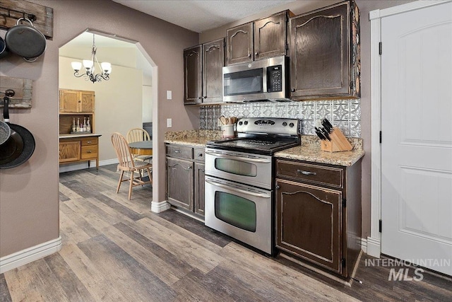 2123 E 3970 N, Filer, ID 83328 - kitchen with appliances with stainless steel finishes, a chandelier, tasteful backsplash, dark brown cabinetry, and light wood finished floors