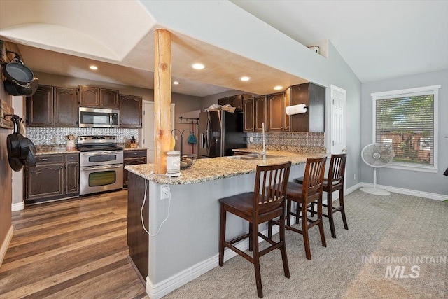 2123 E 3970 N, Filer, ID 83328 - kitchen featuring stainless steel appliances, vaulted ceiling, backsplash, a peninsula, and dark brown cabinetry