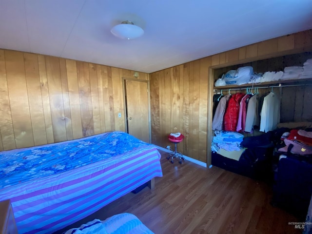 bedroom with hardwood / wood-style floors, wood walls, and a closet